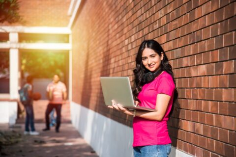 asian-indian-college-student-focus-working-laptop-reading-book-while-other-classmates-background-outdoor-picture-university-campus-min (1)