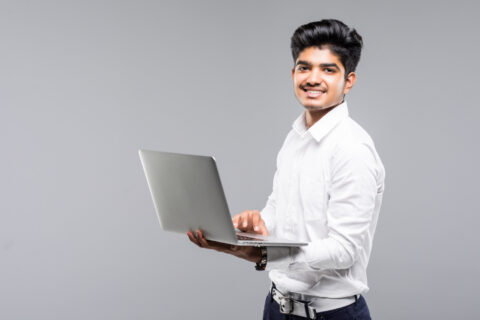 young-indian-man-with-laptop-gray-wall