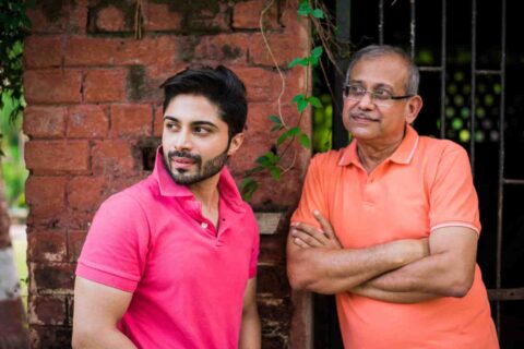 indian-asian-senior-father-son-posing-photograph-while-wearing-jeans-t-shirt-against-red-brick-wall (1)